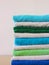 Stack of bath towels on light wooden background closeup.Pile of rainbow colored towels.Top view.