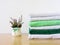 Stack of bath towels on light wooden background closeup.Pile of rainbow colored towels.Top view.