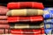 A stack of beautiful woolen blankets in red, blue, yellow, pink. A pile of soft warm blankets in store. Close up. Things for home