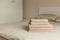 Stack of beige hotel towel on bed in bedroom interior. Vintage toning