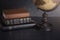 Stack of Bibles and a Globe on a Dark Background