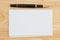 Stack of blank white graph index cards on wood desk with a pen