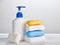 A stack of blocks of solid soap and a bottle of liquid soap on a light background