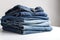 Stack of blue denim clothes on white background, jeans and jacket