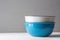 Stack of blue and white ceramic bowls on wood table grey wall background. Cooking baking cookware breakfast concept