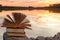 Stack of book and Open hardback book on blurred nature landscape backdrop against sunset sky with back light. Copy space, back to