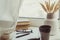 A stack of books, cup of coffee, bouquet of kernels, glasses, notebook and pen over a window.