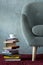 stack of books and cup of coffee on burgundy carpet near grey armchair