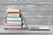 Stack of books with laptop on wooden background