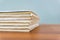 A stack of books are lying on a brown table, documents are stacked close-up