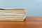 A stack of books are lying on a brown table, documents are stacked close-up