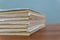 A stack of books are lying on a brown table, documents are stacked close-up