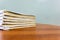 A stack of books are lying on a brown table, documents are stacked close-up