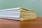 A stack of books are lying on a brown table, documents are stacked close-up