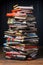 A stack of books, magazines and newspapers sitting on top of a wooden table