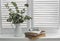 Stack of books,  notebook, glasses,  jug of dry eucalyptus branches on a light window with wooden rustic blinds. Cozy home