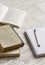 Stack of books, notebook on white wooden table.