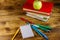 Stack of books, notepad, pens, pencils and apple on wooden desk. Back to school concept