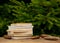 Stack of books and pine cones around on wooden table with spruce branches