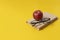 stack of books, red apple and glasses isolated on colorful surface, simple abstract study concept