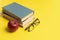 stack of books, red apple and glasses isolated on colorful surface, simple abstract study concept