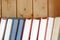 Stack of books standing on bookshelf against wooden wall front view close up