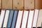 Stack of books standing on bookshelf against wooden wall front view close up