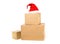 Stack of brown carton cardboard boxes with red santa hat over white background, christmas shopping or online ordering concept