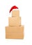 Stack of brown carton cardboard boxes with red santa hat over white background, christmas shopping or online ordering concept