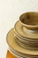 Stack of brown speckled glazed earthenware ceramic plates dishes and bowls on wooden table. White wall background