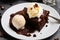 Stack of brownie squares with scoop of ice cream and caramel, white background