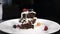 Stack of brownies dessert being decorated with berries on white plate. Falling Berries in Slow Motion. Confectioner