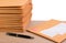 Stack of bubble wrap padded mailing envelopes and pen on white background color over wooden table.