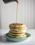 Stack of buttermilk pancakes with maple syrup being poured on top. Copy space.