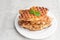 Stack of Caramelized Croissant Waffle or Croffle served in white plate on grey background