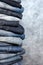 A stack of carelessly folded jeans on gray background. Close-up of jeans in different colors. Copy space