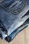 A stack of carelessly folded jeans on wooden background. Close-up of jeans in different colors. Copy space