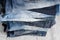 A stack of carelessly folded woman`s jeans on gray background. Close-up of jeans in different colors. Selective focus
