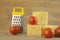 Stack cheese cubes and chery tomatoes with miniature grater on a wood kitchen table