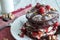 Stack of chocolate pancakes topped wtih cherry and walnuts, sprinkled with powdered sugar and drizzled with maple syrup. Gourmet B