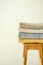 Stack of clean folded terry towels on wooden high stool white wall background. Laundry spa wellness cleanliness concept. Provence