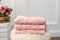 Stack of clean soft pink towels with lace and pearls. Flowers on background
