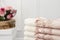 Stack of clean soft white and pink towels with lace and pearls. Flowers on background