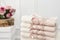 Stack of clean soft white and pink towels with lace and pearls. Flowers on background