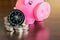 Stack of coins with compass and piggy bank on wood table