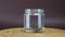 Stack of coins are falling in glass moneybox on brown background, rotation shot. Person puts money coins into glass jar. Business