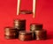 Stack of coins on the red textile background and add one more with food sticks. Selective focus
