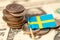 Stack of coins with Sweden flag on USA dollar banknotes