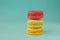 Stack of colorful macaroons stacked up like a tower in turquose pastel background.