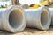 Stack of concrete drainage pipes for wells water discharges laying an external sewage system at a construction site